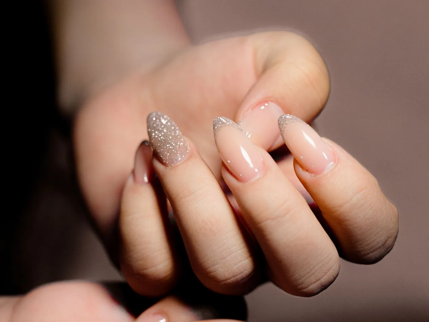 Two hands showing different neutral gel nail finishes
